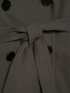 Detail view of deep olive trench coat featuring four-hole resin buttons and belted waist