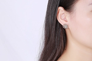 Close-up of model wearing silver hollow clover rhinestone earrings in stainless steel