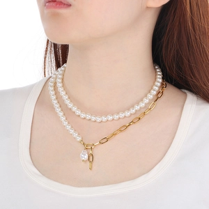 Close-up of double-layered baroque pearl and gold chain necklace worn on a white shirt