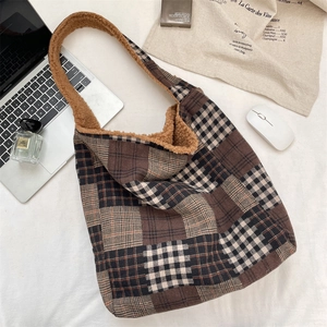 Close-up of brown plaid tote bag with faux shearling lining and laptop on white surface