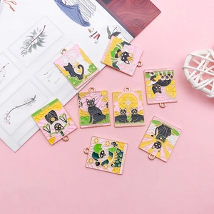 Detailed view of tarot card charms with black cat enamel designs on floral background