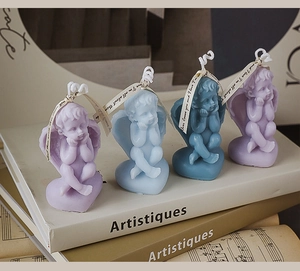 Detailed view of four angel soy wax candles with heart bases on artistic books