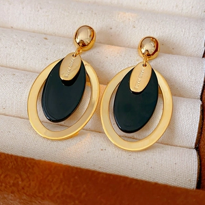 Macro detail of handmade gold oval resin earrings with metallic finish on jewelry display