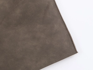 Detail of dark gray faux leather grain and precise stitching on a reversible coat