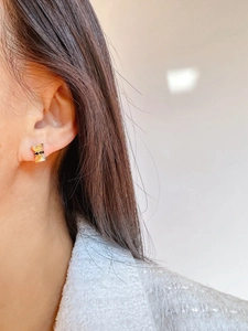 Detail view of golden bow earrings with black crystals on a model's ear