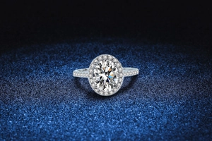 Macro detail of oval cut moissanite ring with halo setting on blue textured background