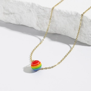 Detailed close-up of rainbow striped bead pendant on gold chain atop white textured stone