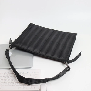 Black quilted laptop sleeve with wide shoulder strap shown with keyboard and mouse