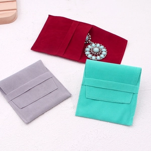 Close-up of velvet jewelry pouches in red, grey, and mint green with flap closure