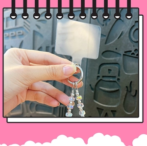 Detailed macro view of clear phone tether tab with iridescent crystal-beaded charm