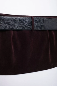 Détail de la texture en velours bordeaux et de la ceinture noire avec effet crocodile