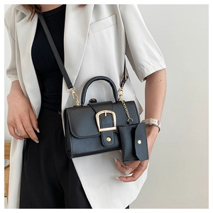 Detail of black pebbled leather crossbody bag with gold D-buckle and mini coin purse
