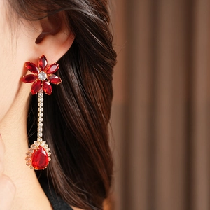Close-up of red zircon flower and water drop earrings on a model with golden finish