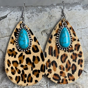 Detailed shot of leopard print cowhide teardrop earrings with turquoise stones and silver hooks
