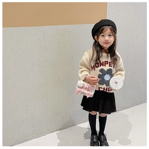 Pink satin bow handbag styled with a girl's knitted sweater and pleated skirt outfit