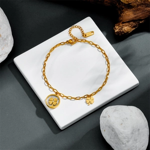 Macro shot of gold-plated clover charms on a stainless steel bracelet with S.STEEL hallmark