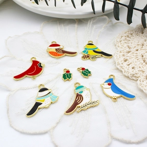 Detail of colorful enamel bird charms including Christmas birds and holly leaves