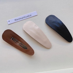 Detail of three leather BB hair clips in brown, beige, and black with metal backing