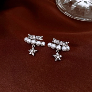 Detailed shot of silver double-layered ear clip with pearls, zircons and star pendant