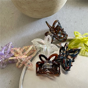 Detailed view of six colorful butterfly hair claws in acetate on a decorative silver tray