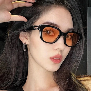 Fashionable thick black frame sunglasses with orange lenses and silver cross earring