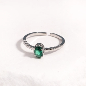 Macro view of adjustable silver ring featuring a claw-set green oval gemstone