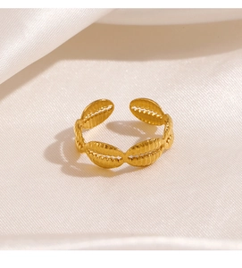 Detail of adjustable gold shell-patterned stainless steel ring on silk background