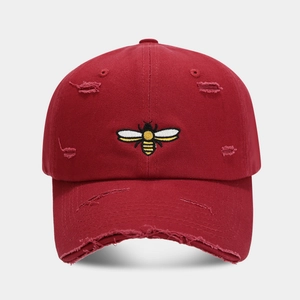 Detail of burgundy baseball cap with bee embroidery and distressed vintage ripped effects
