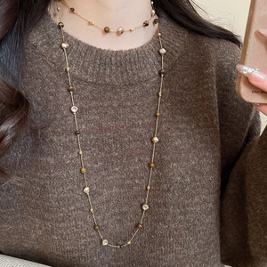 Detail of layered gold chains with tiger eye beads and freshwater pearls on sweater