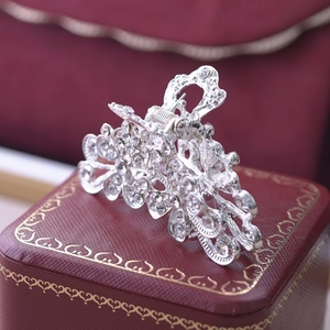 Detail of silver alloy hair claw clip with intricate hollow patterns and sparkling rhinestones