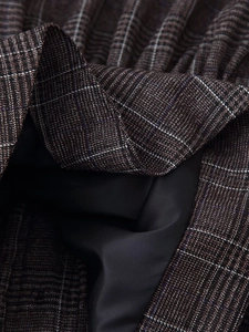 Détail du tissu en laine à carreaux café avec doublure en satin noir lisse et brillant