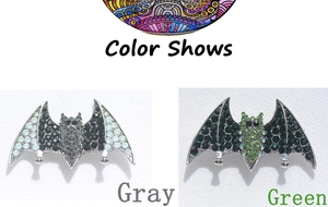 Detail view of gothic style bat brooches in grey and green rhinestones on white leather