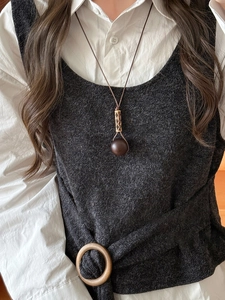 Detail of vintage geometric wood and resin pendant necklace worn on a white shirt