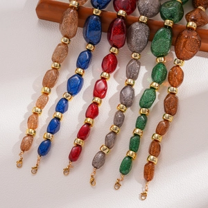 Macro shot of colorful acrylic resin beads with glitter and gold metal lobster clasps