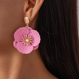 Elegant pink flower earrings with pearl center and golden stud worn by a model