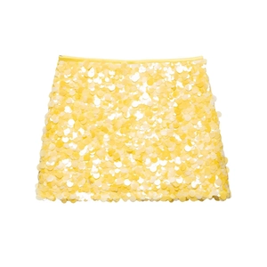 Vue à plat d'une mini-jupe jaune à paillettes ornée de grands disques brillants ronds
