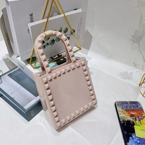 Detailed shot of pink PVC mini crossbody bag with studs on a stylish bookshelf