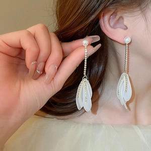 Detail of elegant white floral tassel earrings with pearls and rhinestones on ears