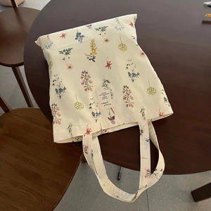 Detailed close-up of a floral cotton canvas tote bag with woven label on a wooden table