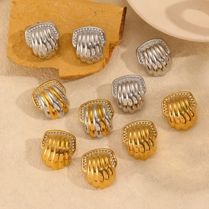Elegant 18k gold shell earrings with pavé zircons displayed on natural stones