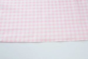 Close-up of pink and white plaid fabric texture with detailed stitching and soft weave
