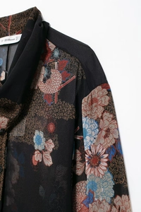 Detail of floral chiffon shirt with neck binding and brand label in flat lay view