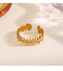 Detail of 18K gold plated fishbone ring with white enamel drip oil finish on beige surface