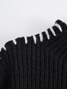 Dettaglio di un maglione nero in maglia spessa con cuciture decorative bianche a contrasto