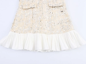 Détail du tissu en tweed à paillettes avec un élégant ourlet plissé en mousseline blanche