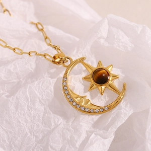 Macro shot of 18K gold star and moon pendant with crystals and brown gemstone on chain