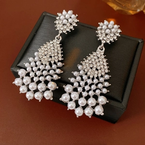Detail of silver drop earrings with white pearls and sparkling rhinestones on jewelry box