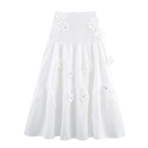 Detailed macro view of 3D floral appliques and rhinestones on a white tiered skirt