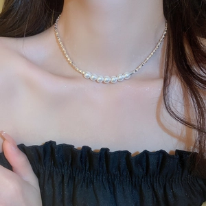 Gros plan d'un collier de perles porté par un mannequin avec chaîne argentée