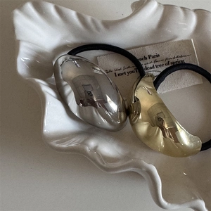 Macro view of metallic minimalist irregular hair ties in gold and silver finish
